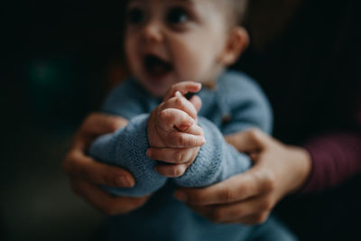 Midsection of mother holding baby boy hands