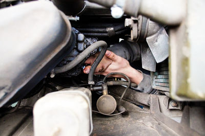 Cropped hand of mechanic repairing motor vehicle at auto repair shop