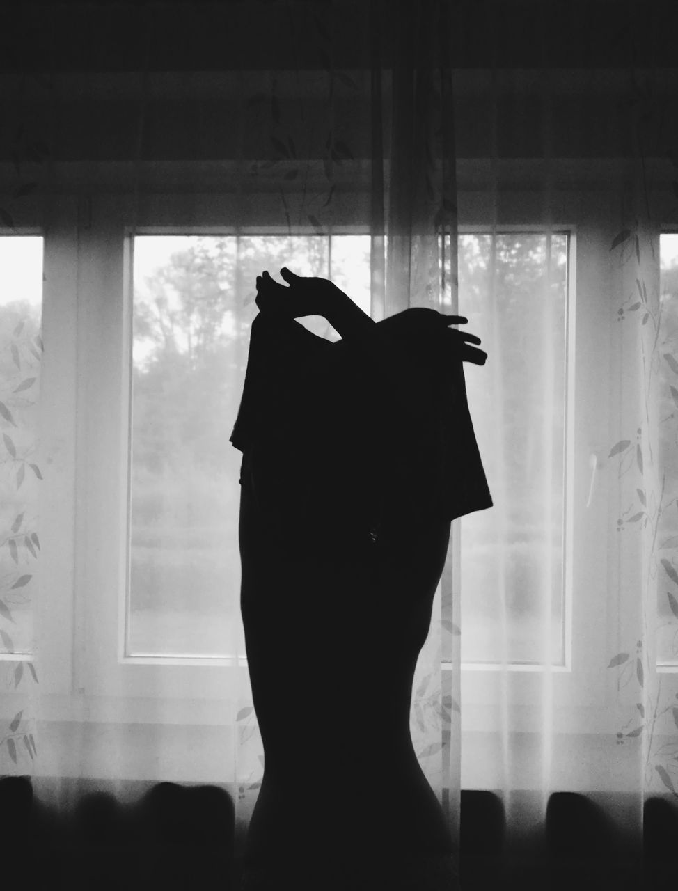 REAR VIEW OF SILHOUETTE WOMAN STANDING AT HOME