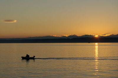 Silhouette boat in sea against sky during sunset