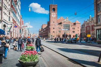 People walking on road by buildings in city