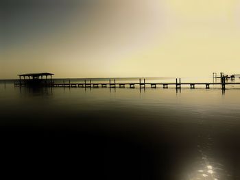 Pier over sea against sky during sunset