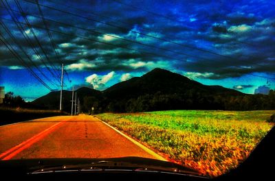 Country road against cloudy sky