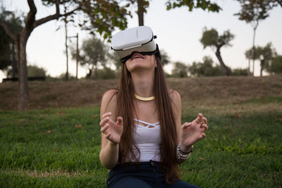 Young woman using virtual reality simulator while enjoying at park