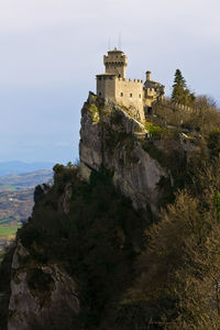 Castle on hill against cloudy sky