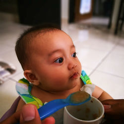 Cropped hands of person feeding baby girl at home