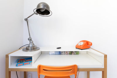 Close-up of electric lamp on table against wall