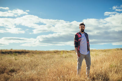 Young man standing on field against sky