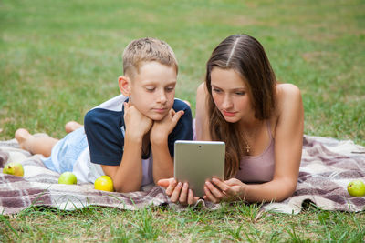 Friends lying on grass while looking at camera