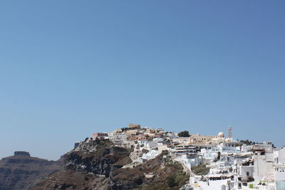 Buildings in city against clear blue sky