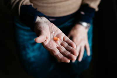 From above of crop unrecognizable senior woman with pills in hand at home