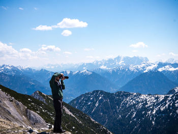 Man standing on snow covered mountain against sky