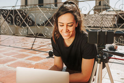 Young sporty fit woman coach doing online lessons through video call on her mobile phone