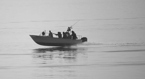 People in boat sailing on sea against sky