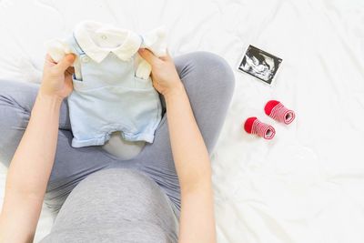Low section of woman sitting on bed