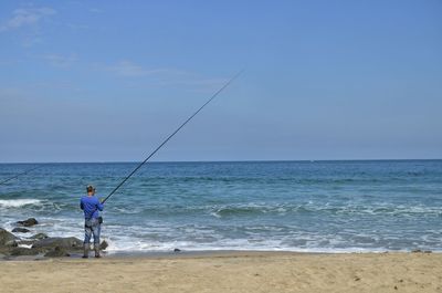 Rear view of man fishing at beach
