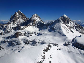 Scenic view of snowcapped mountains against clear blue sky