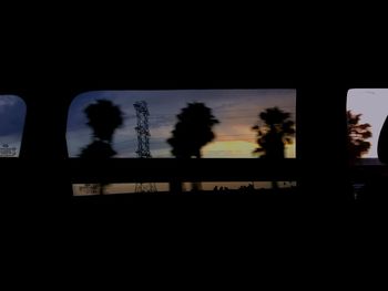 Silhouette trees against sky seen through window