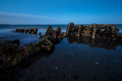 Rocks on beach against blue sky