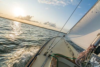 Sailboat sailing on sea against sky during sunset