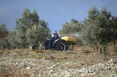 Tractor on field against trees