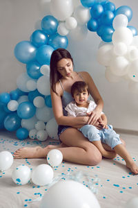 Mom and son on their birthday having fun at home with balloons and number two