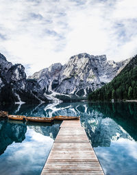 Pier over lake by mountains against sky