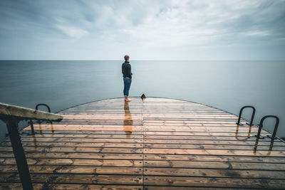 Man standing on pier by sea against sky