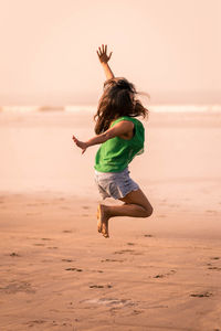 Rear view of girl jumping on beach