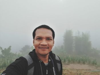 Portrait of smiling man standing on land against sky