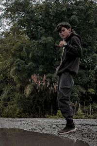 Full length of young man standing against trees