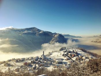 Mountain and snow covered houses against clear sky