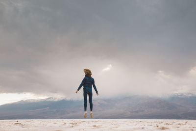 Full length of woman jumping on field against sky