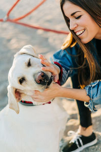 Cheerful woman petting dog at playground during sunset