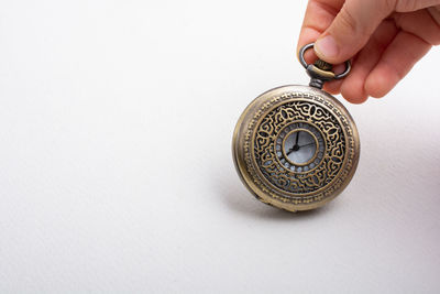 Close-up of hand holding ring over white background