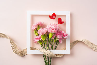 Directly above shot of pink rose on table against white background