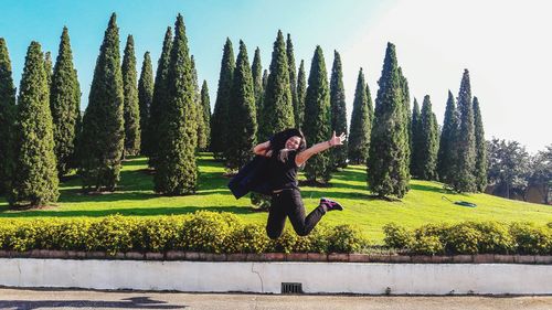 Front view of woman jumping against trees