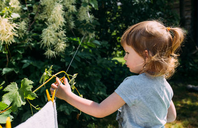 Little preschool girl helps with laundry. child washes clothes in garden