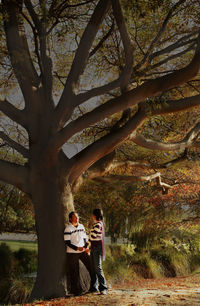 Couple holding hands while standing below tree during autumn