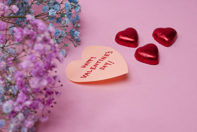 Heart-shaped candies and love message on pink background