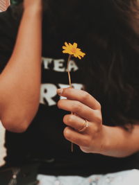 Midsection of woman holding yellow flower