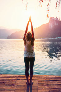 Woman doing yoga on pier against lake