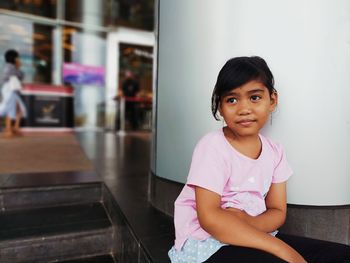 Portrait of a smiling girl sitting on wall