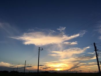 Low angle view of silhouette electricity pylon against sky during sunset