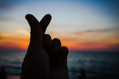 Close-up of silhouette hand against sky during sunset