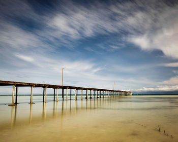 Pier on beach against sky