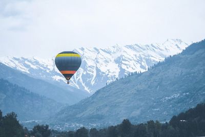 Hot air balloon flying over mountain against sky