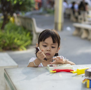 Close-up of cute girl playing with childs play clay at table outdoors