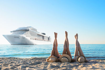 People relaxing on beach against clear sky