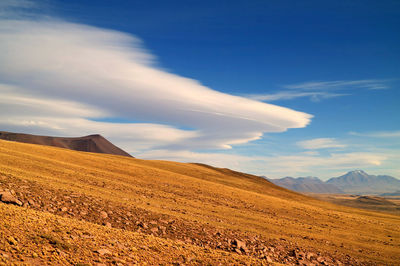 Arid foothill of los flamencos national reserve with lenticular clouds in the backdrop, chile